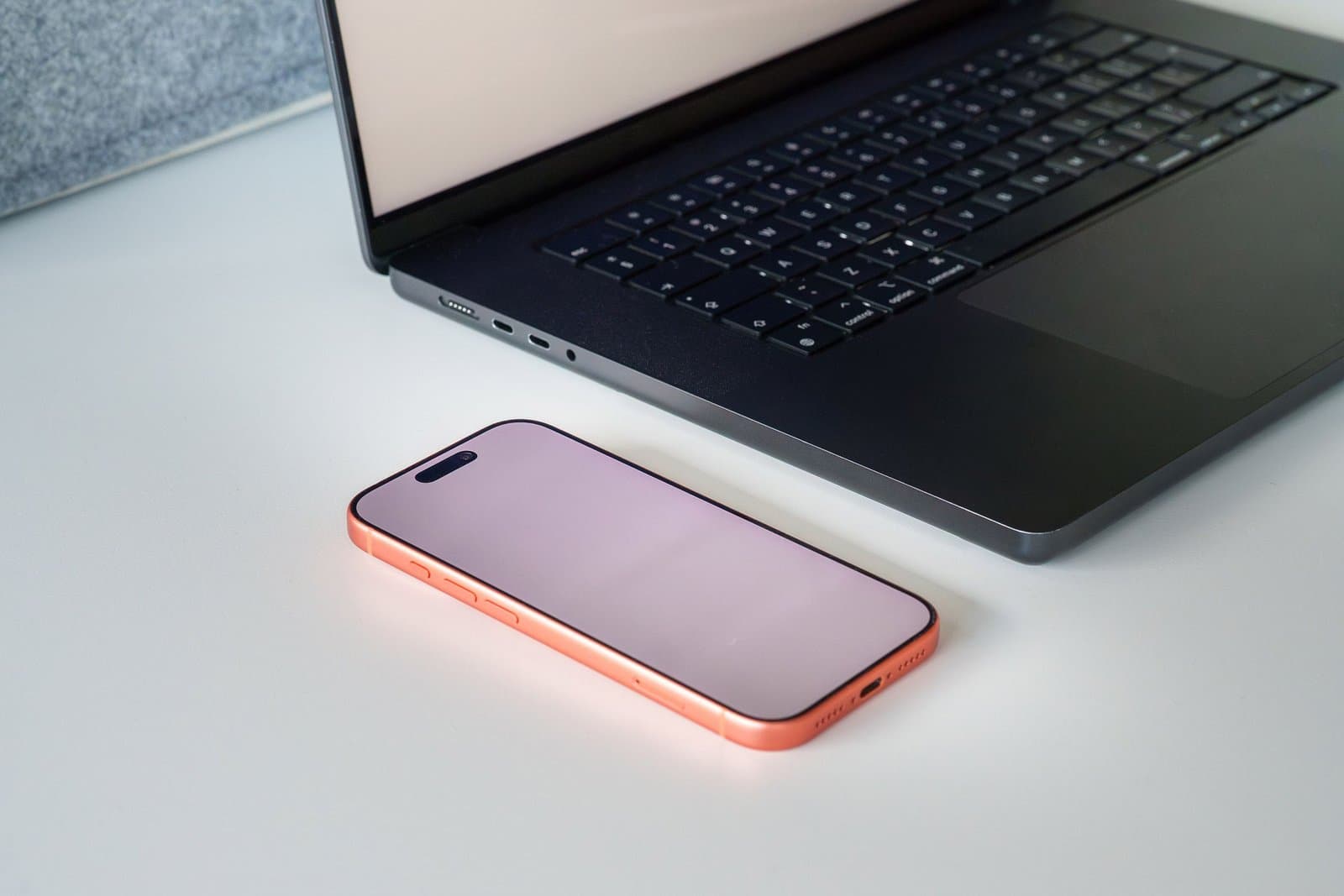 A laptop and a smartphone side by side on a white desk