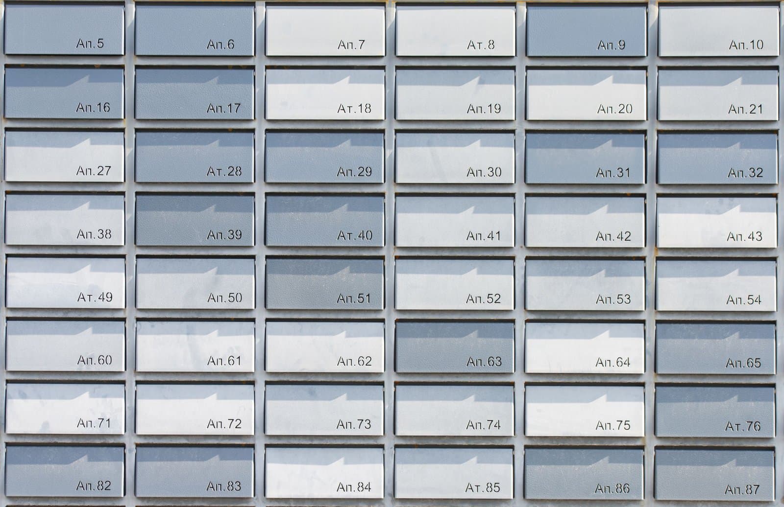 A wall of grey metal mailboxes in a neat numbered grid, lit by daylight